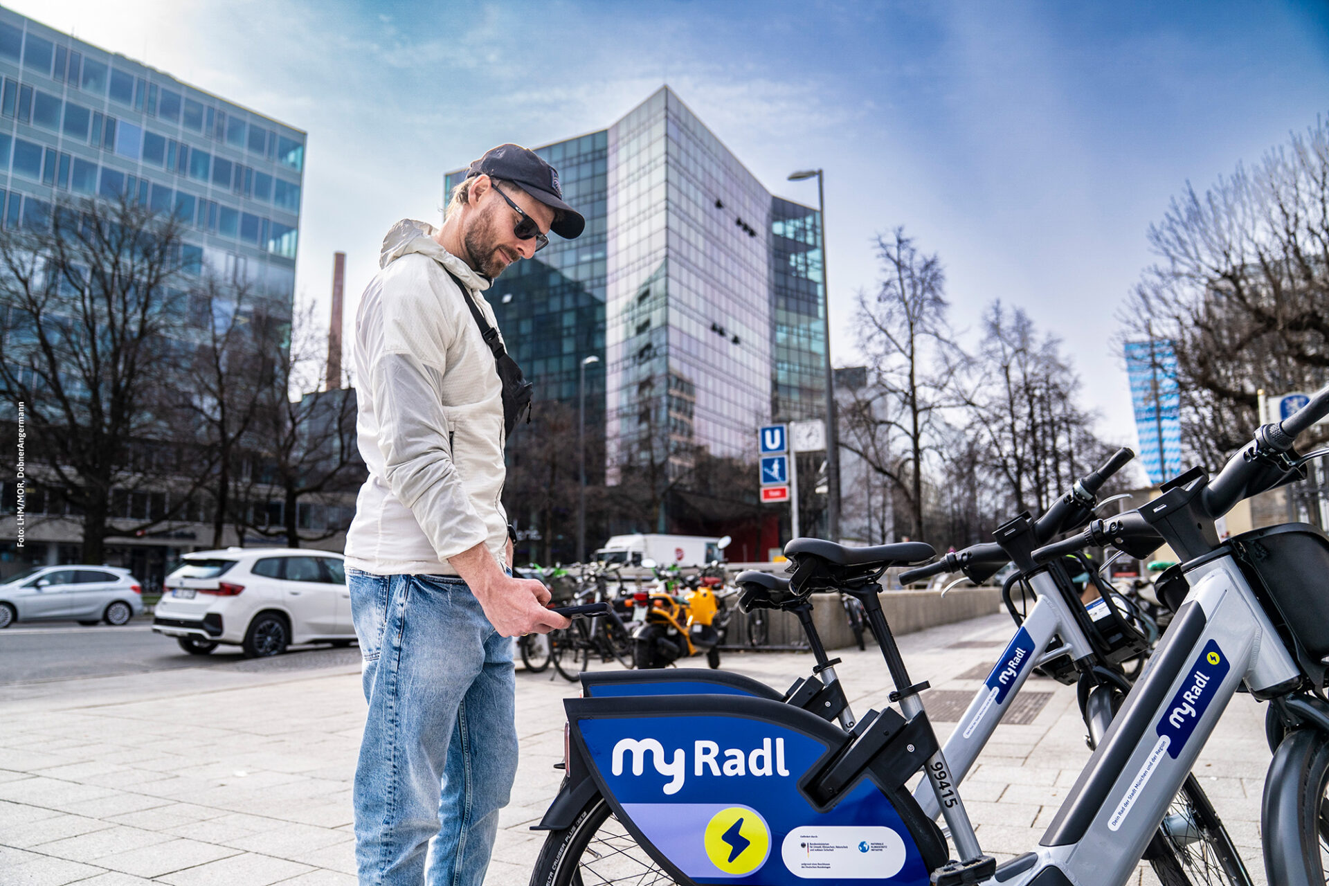 Ein Mann scannt mit seinem Handy den QR-Code an einem MyRadl Leihrad, um es auszuleihen.